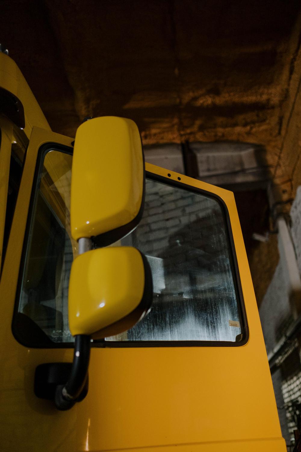 Oglinzile galbene ale unui camion, lângă ușa cabinei.