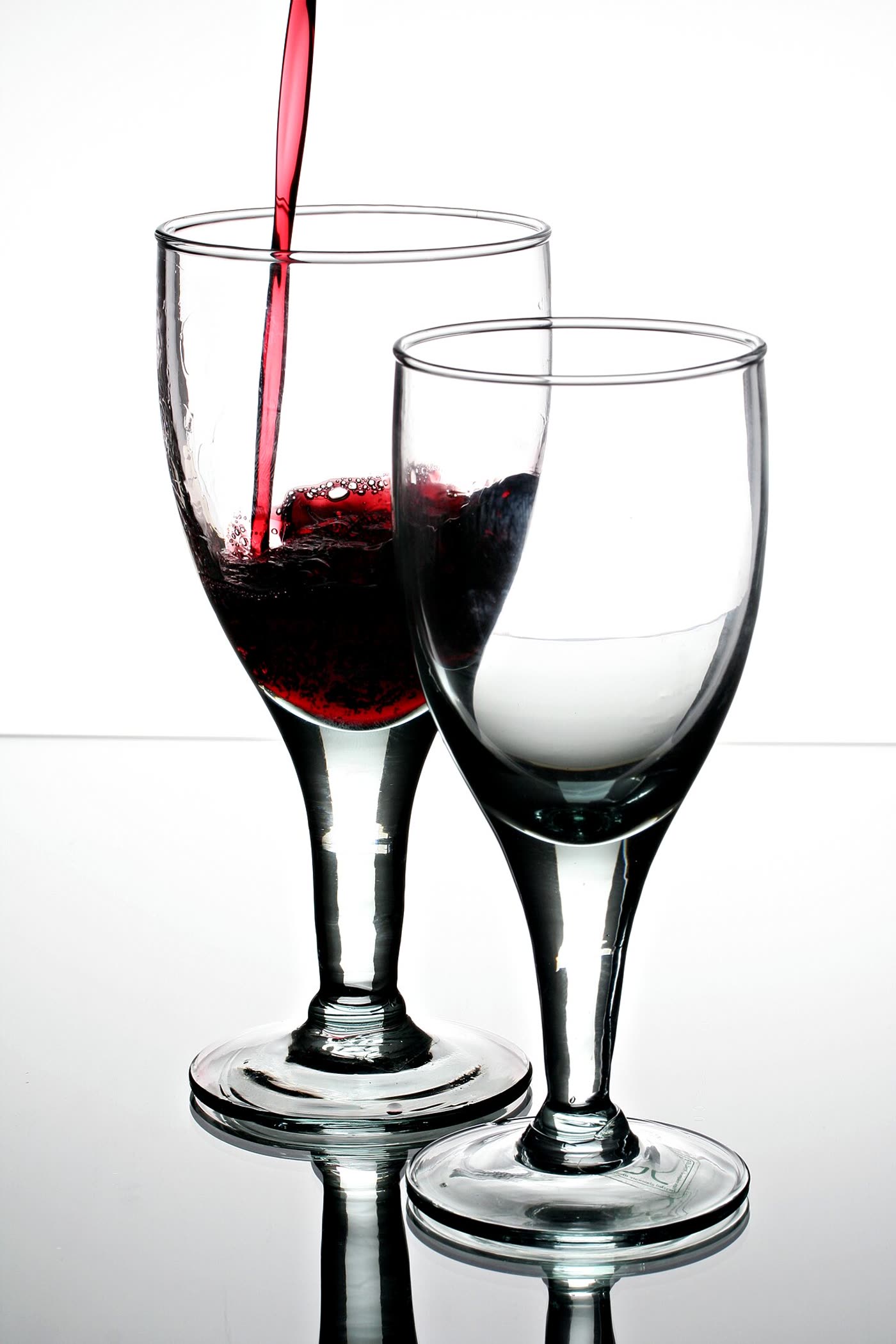 Red wine poured into two coupe glasses