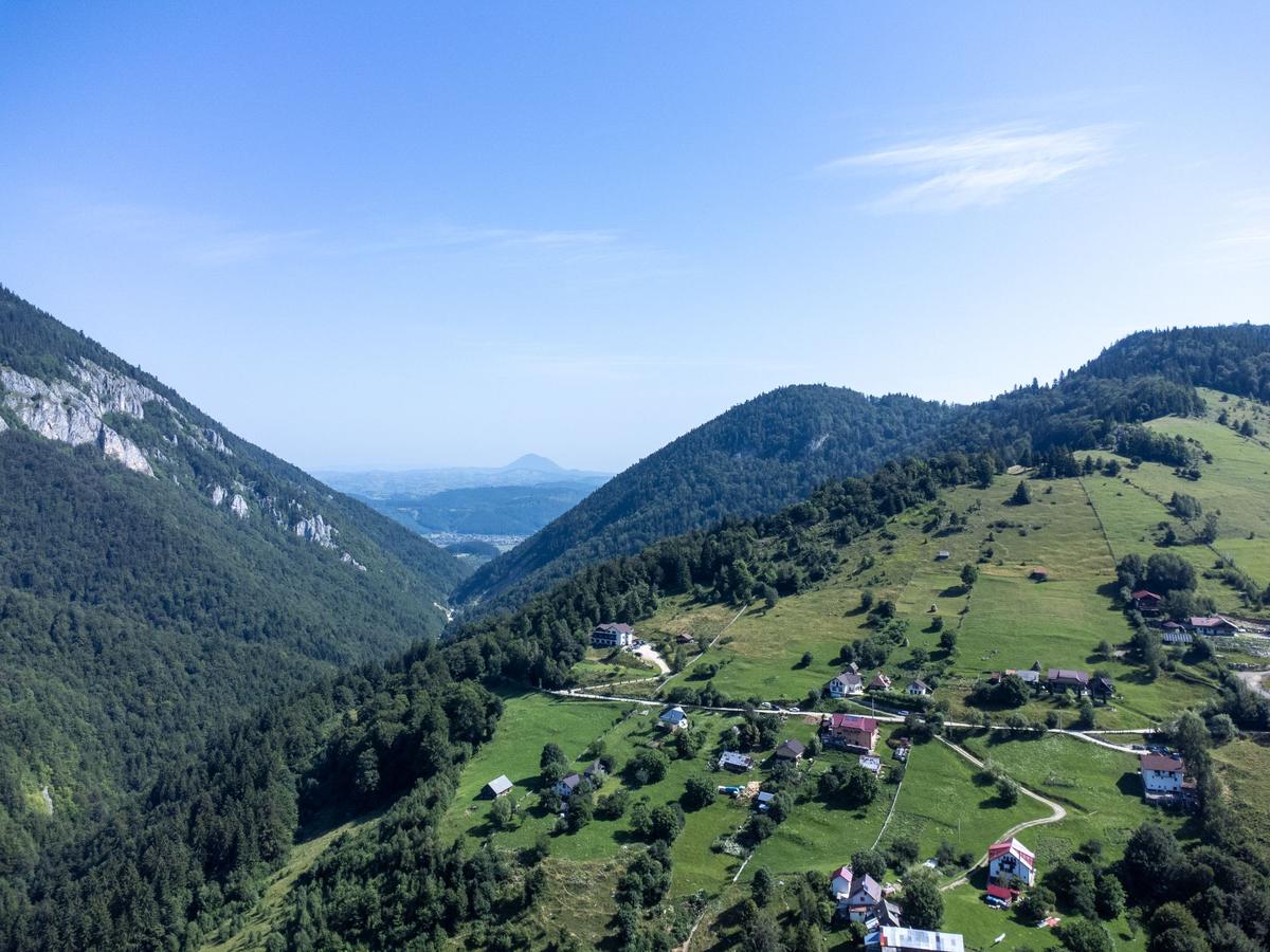 Satul Măgura văzut de sus: case risipite pe pajiști verzi, între versanți împăduriți