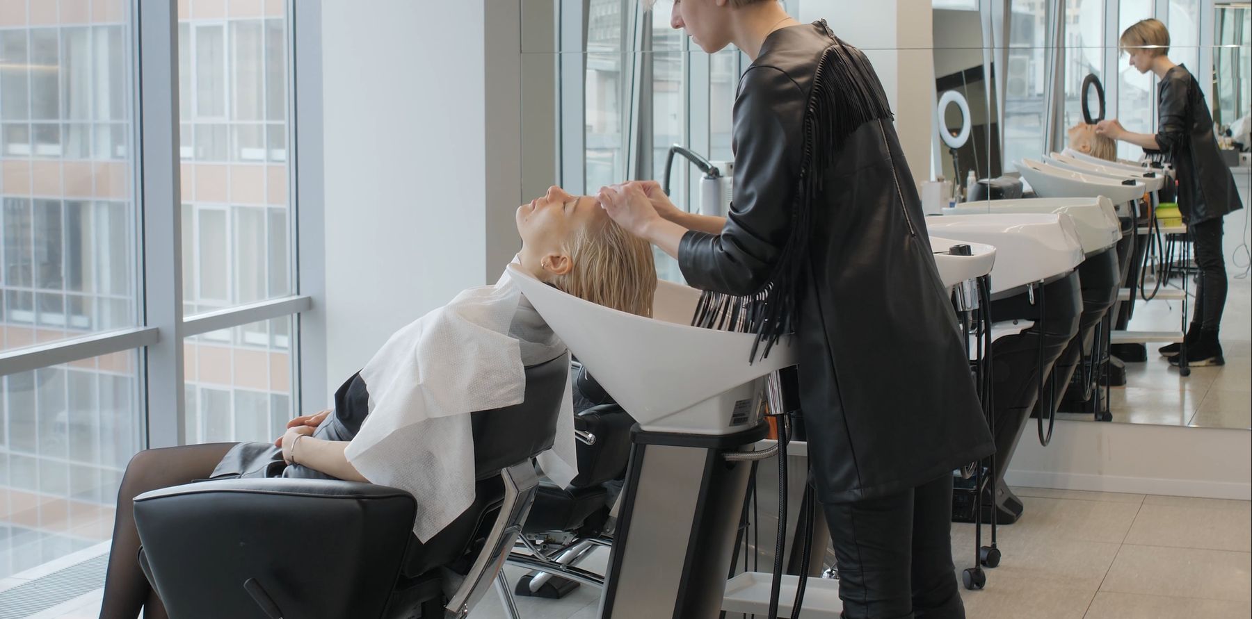 Salonul: rândul de chiuvete albe lângă geamurile înalte, Ilinca la o clientă.