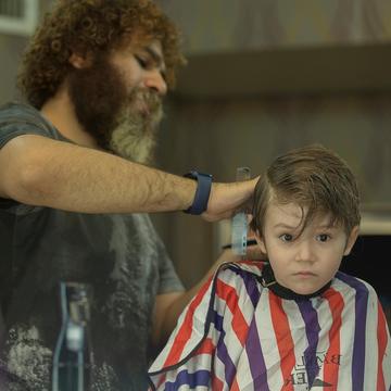 Arman tunde un băiat cu pelerina cu dungi, care se uită fix înainte.